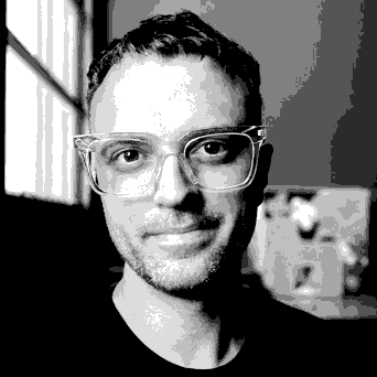 Dithered black-and-white pixel portrait of Simon: short hair, stubble, clear-framed glasses, slight smile